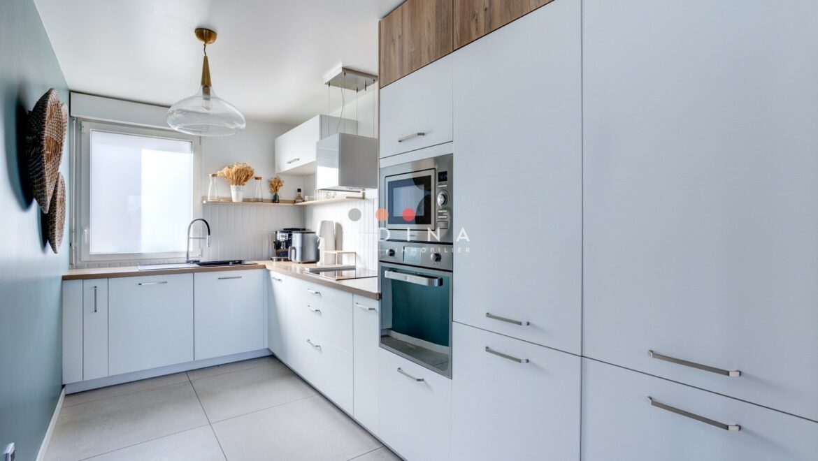 Cuisine moderne avec meubles blancs et électroménagers intégrés.