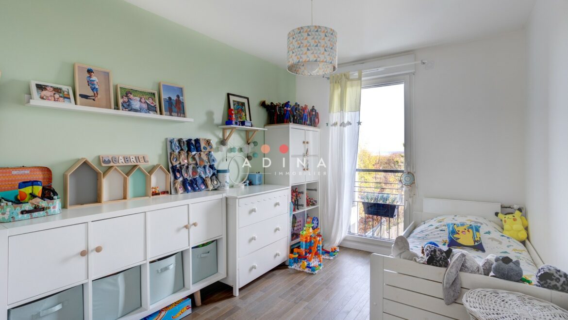 Chambre d'enfant lumineuse avec jouets et meubles blancs.