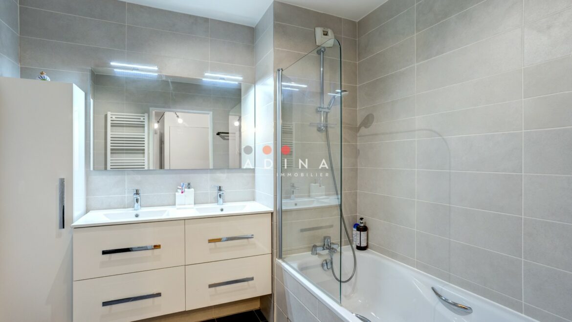 Salle de bain moderne avec double vasque et baignoire.