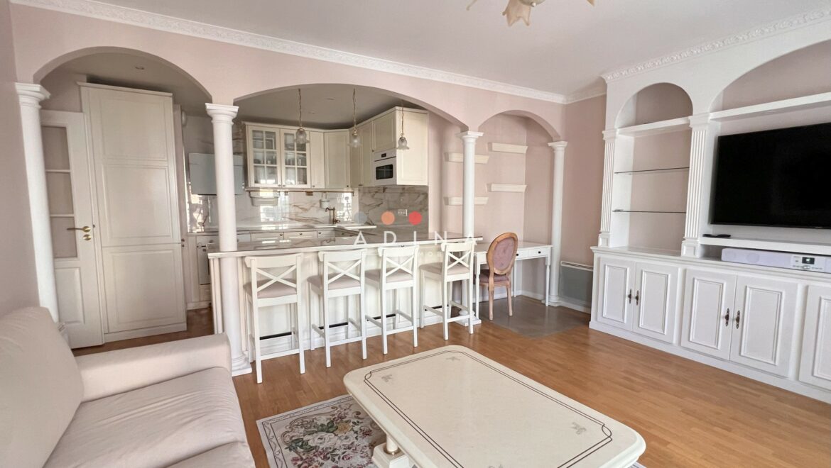 Salon lumineux avec cuisine ouverte et décoration classique.