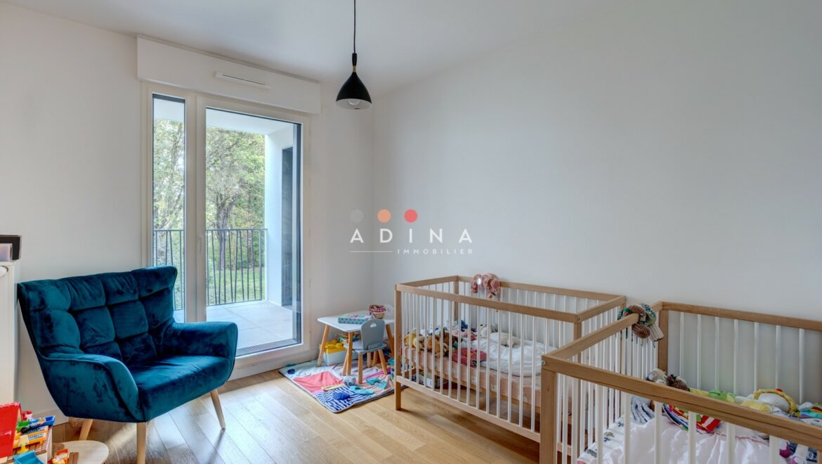 Chambre d'enfant avec deux lits et fauteuil bleu.