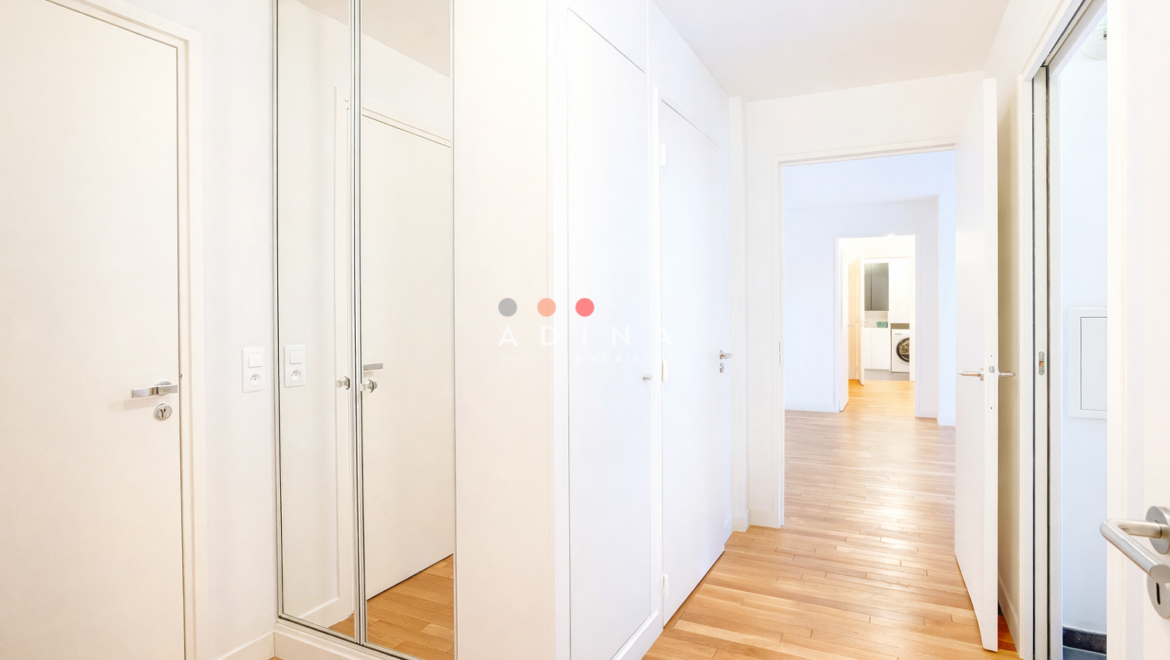 Couloir moderne avec parquet et portes blanches.