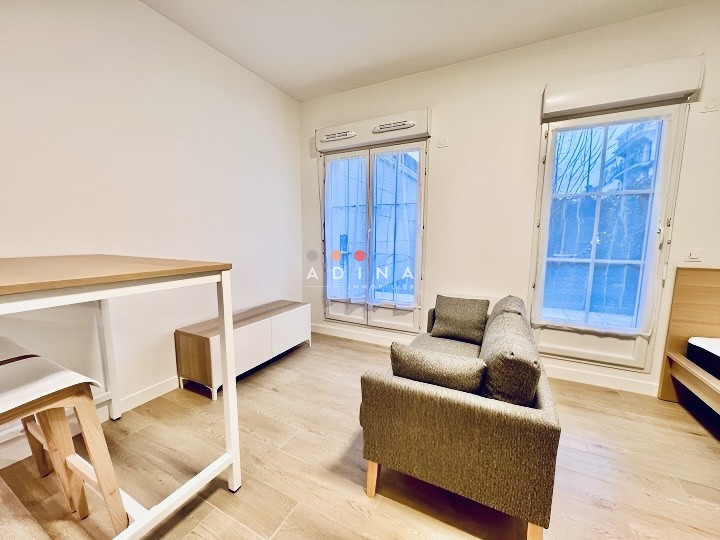 Petite salle de séjour meublée avec grandes fenêtres.