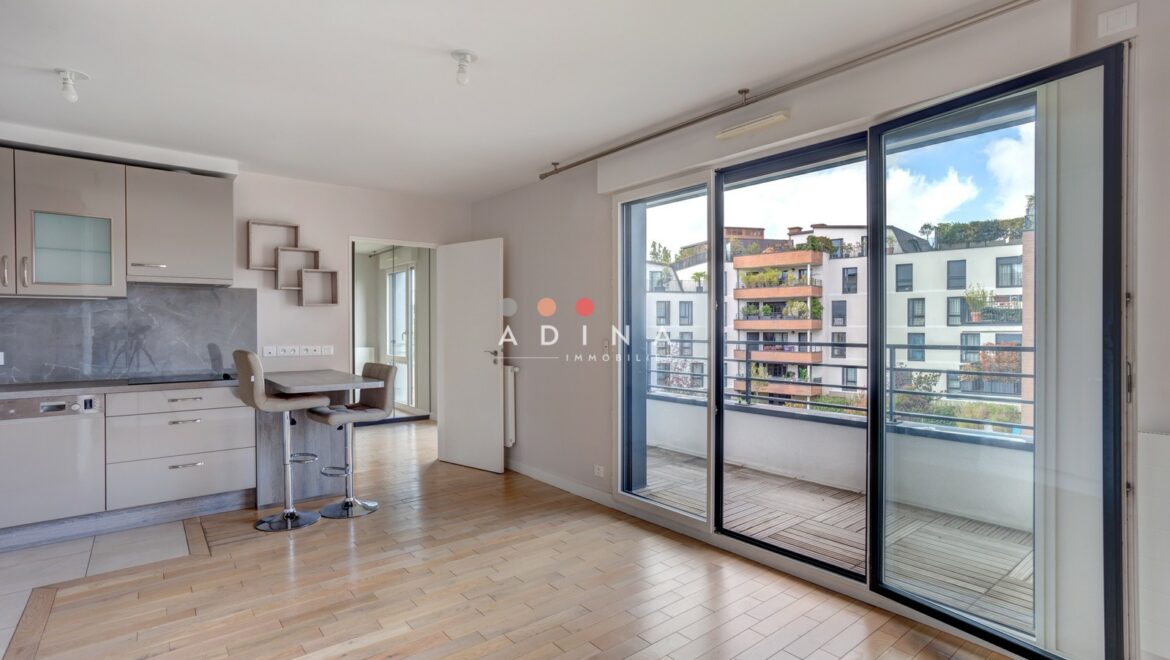 Appartement lumineux avec balcon et vue sur des immeubles modernes.