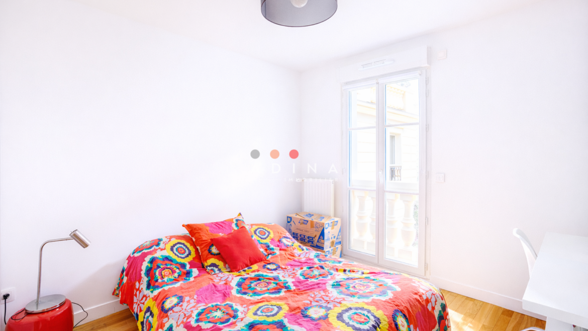 Chambre lumineuse avec lit coloré et grande fenêtre.