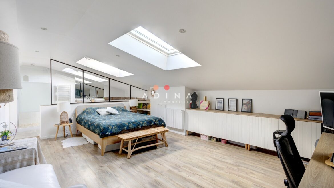 Chambre mansardée lumineuse avec des fenêtres de toit.