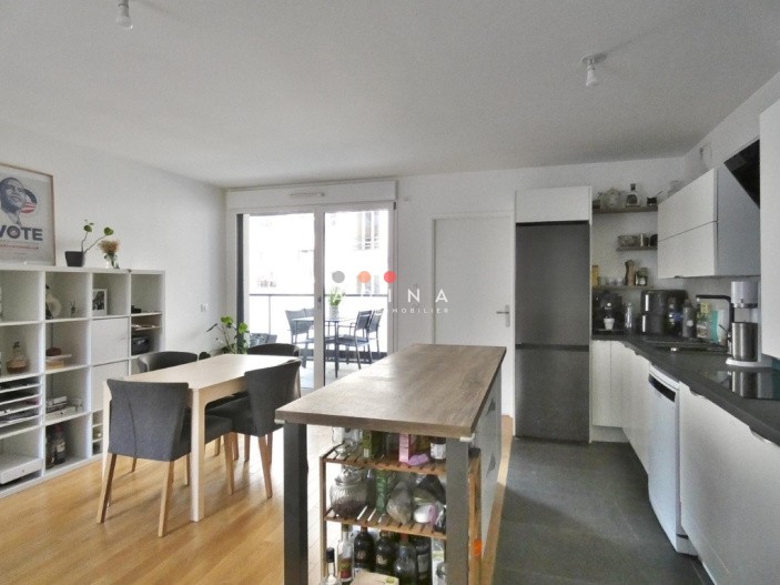 Salle à manger avec cuisine ouverte et verrière.