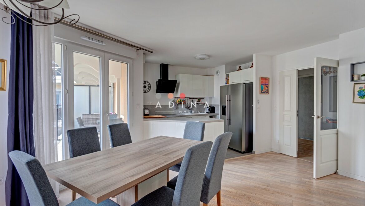 Cuisine moderne ouverte avec table à manger en bois.