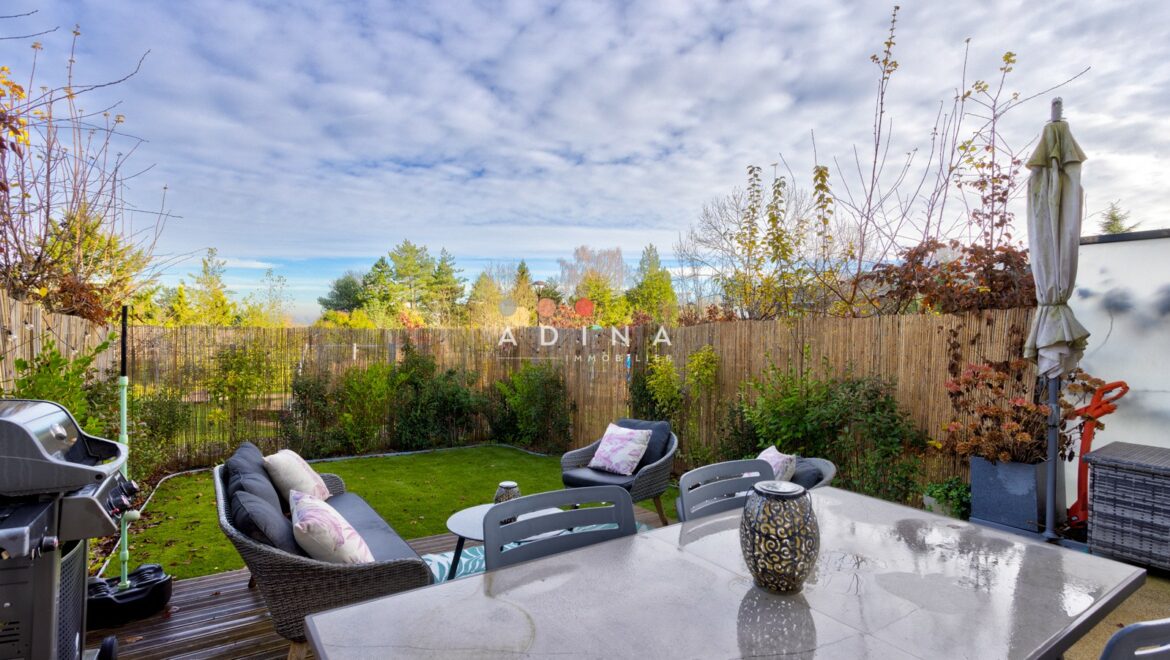 Terrasse avec mobilier de jardin verdoyant.
