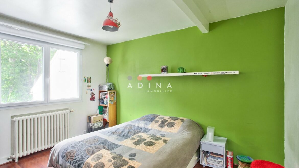 Chambre avec mur vert et lit au Plessis-Robinson.