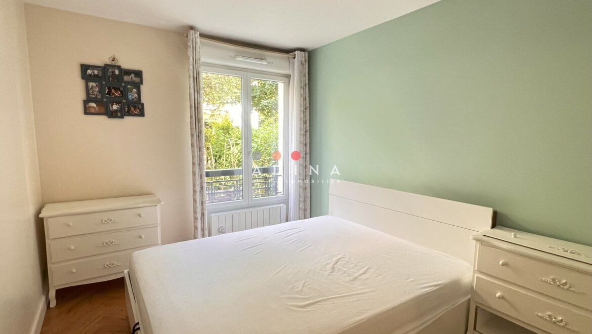 Chambre lumineuse avec lit double et commodes blanches.