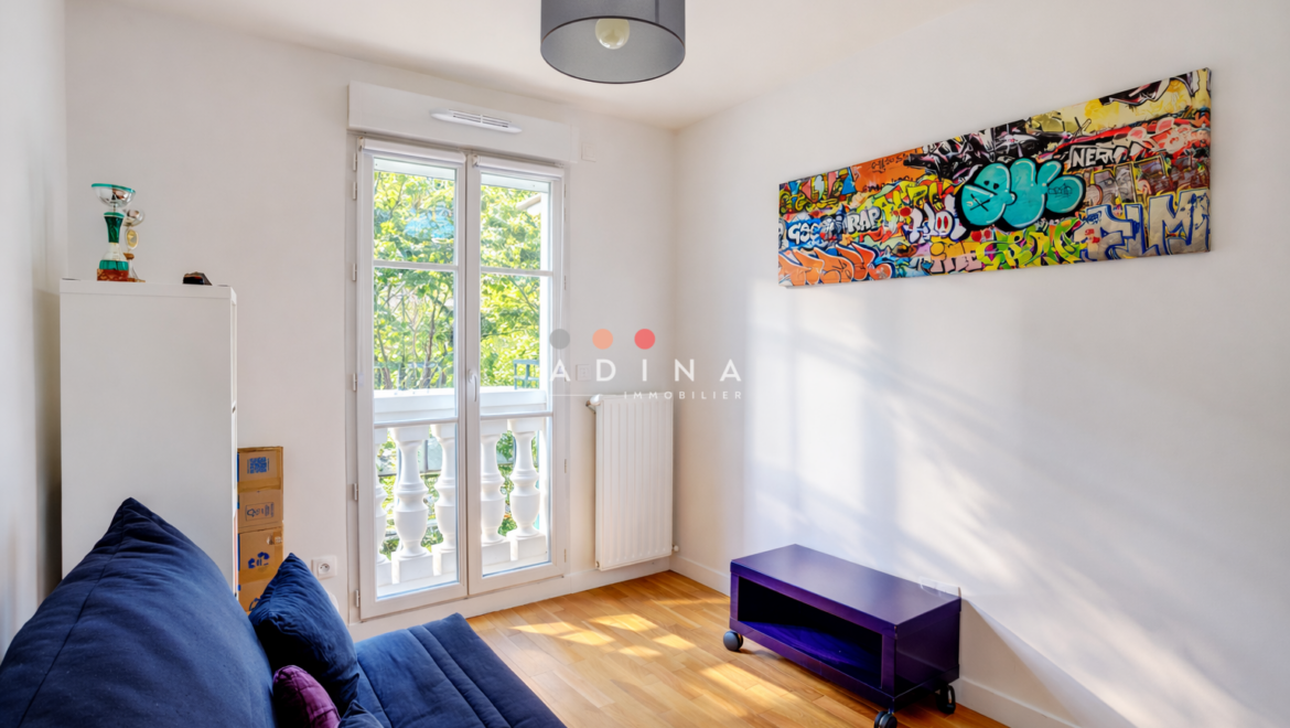 Petite chambre lumineuse avec canapé bleu et déco murale colorée.