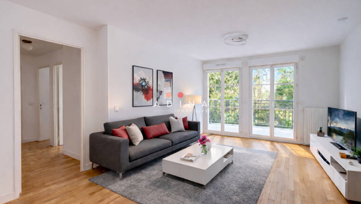 Salon moderne et lumineux avec parquet et baies vitrées.