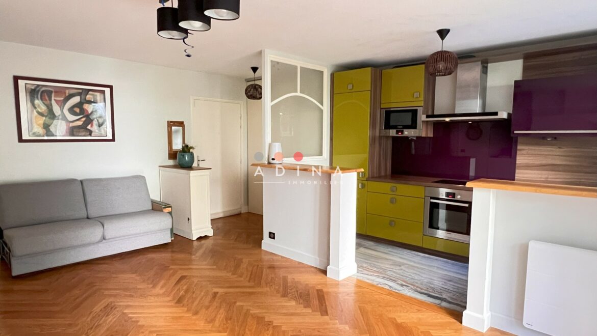 Salon moderne avec cuisine ouverte et parquet au sol.