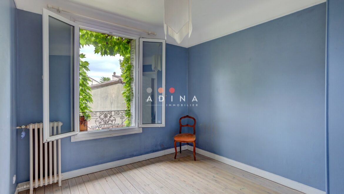 Chambre vide avec murs bleus et fenêtre ouverte.