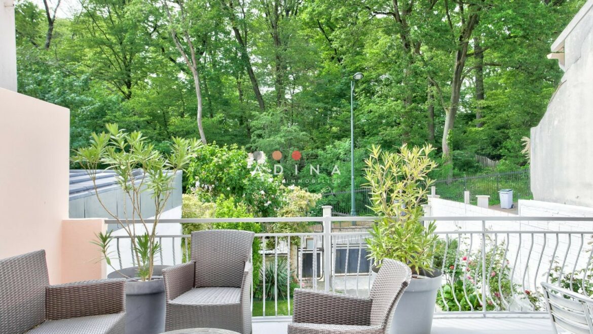 Terrasse avec salon de jardin et vue sur espace vert.
