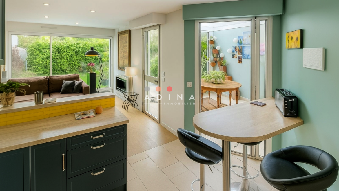 Cuisine moderne avec vue sur le salon et un jardin.