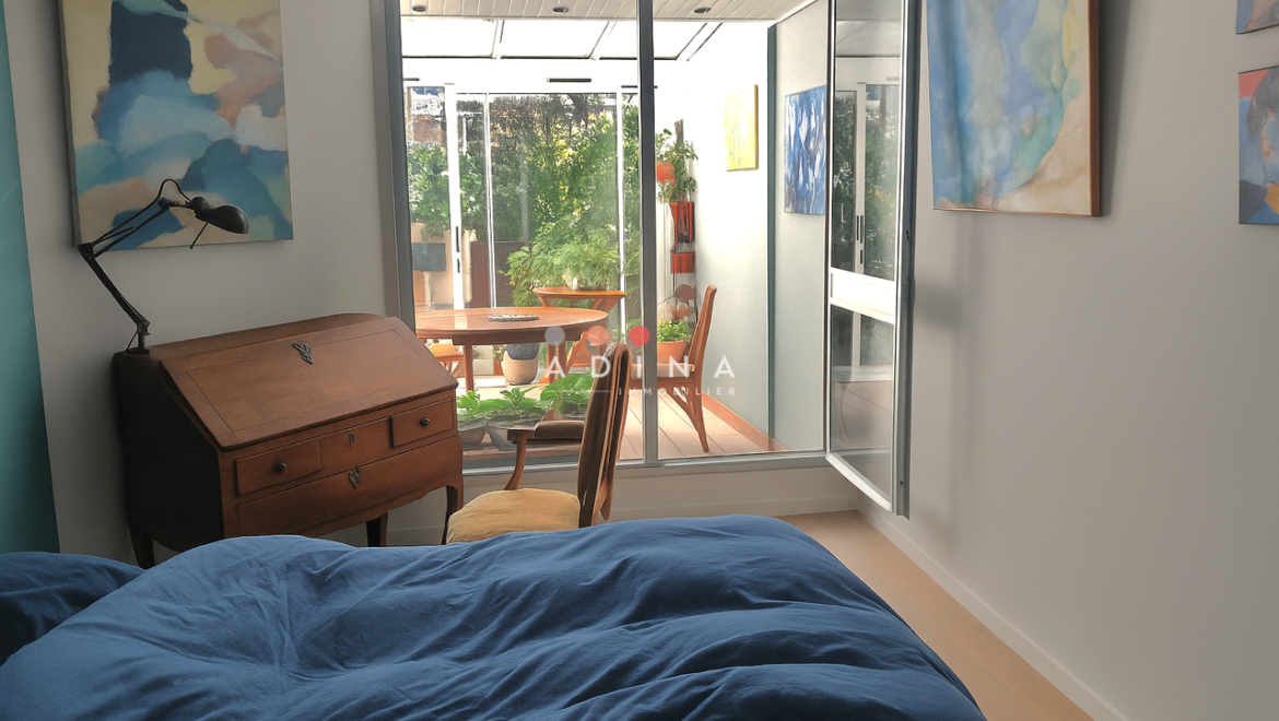 Chambre lumineuse avec bureau en bois et accès à la terrasse.