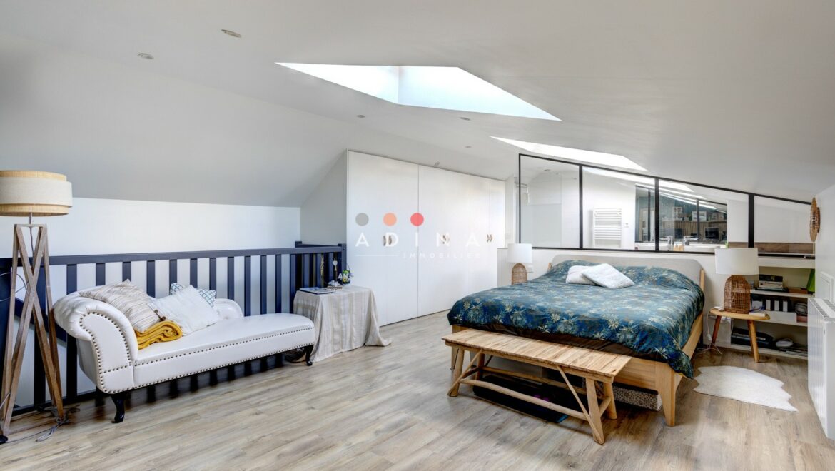 Chambre mansardée avec mobilier moderne et puits de lumière.