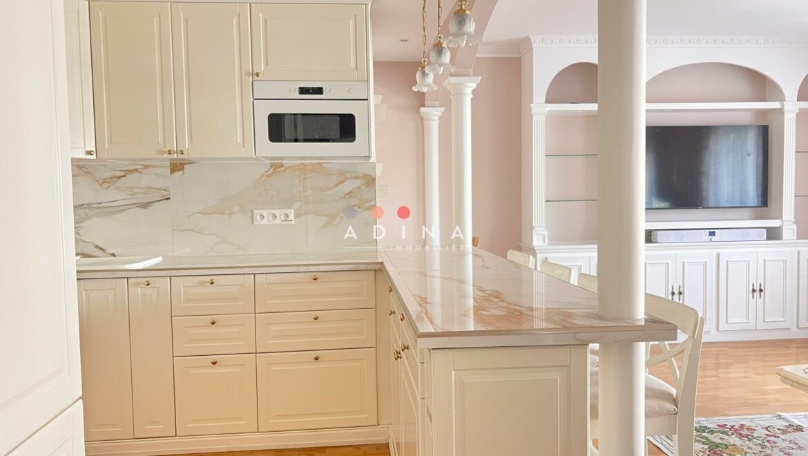 Cuisine moderne avec bar et mobiliers blancs.