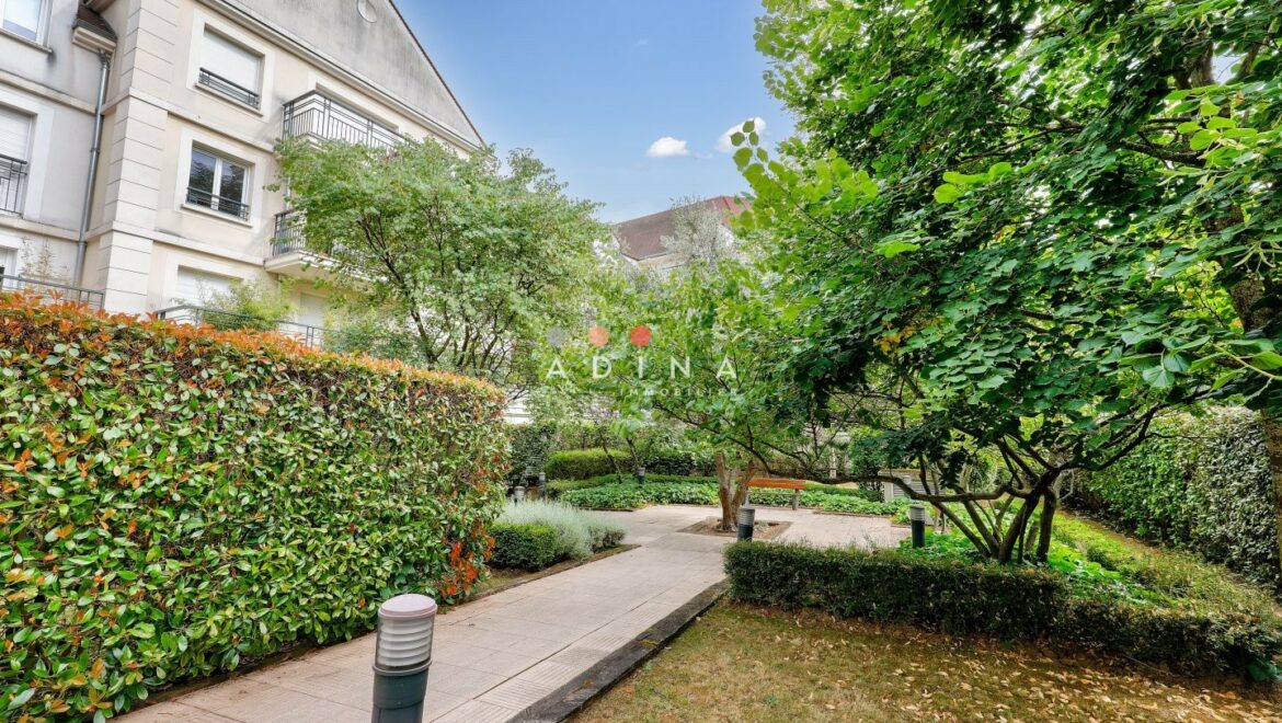 Jardin avec allée et immeuble résidentiel.