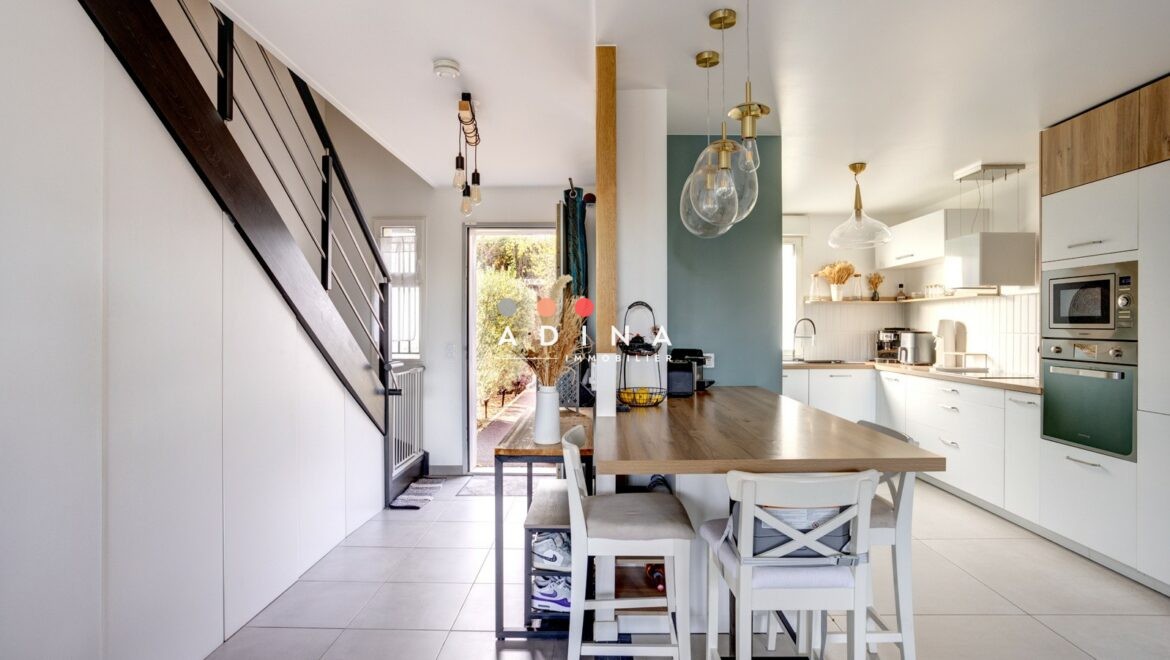 Cuisine moderne avec îlot central et grande table à Louveciennes.