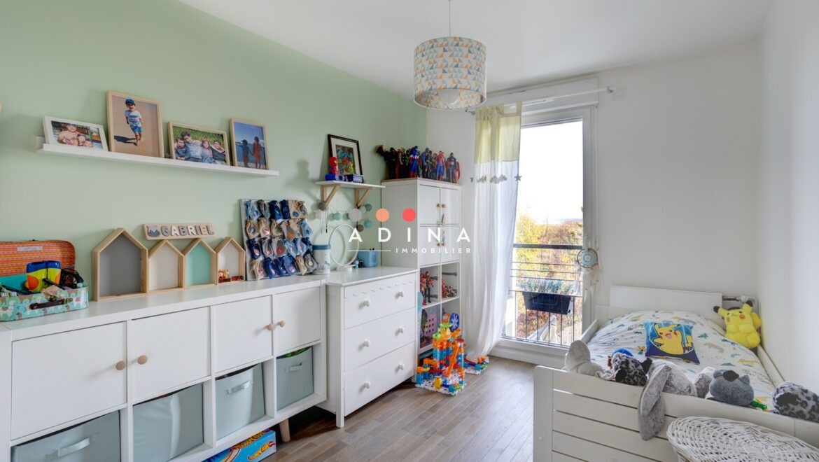 Chambre d'enfant lumineuse avec meubles blancs et décorations colorées.