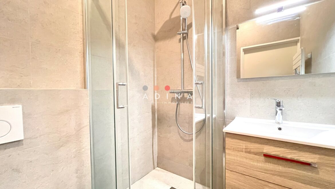Salle de bain moderne avec douche en verre et meuble lavabo.