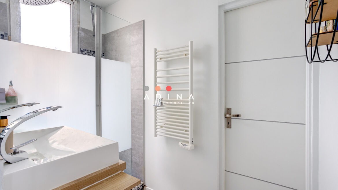 Salle de bain moderne avec douche italienne et lavabo.