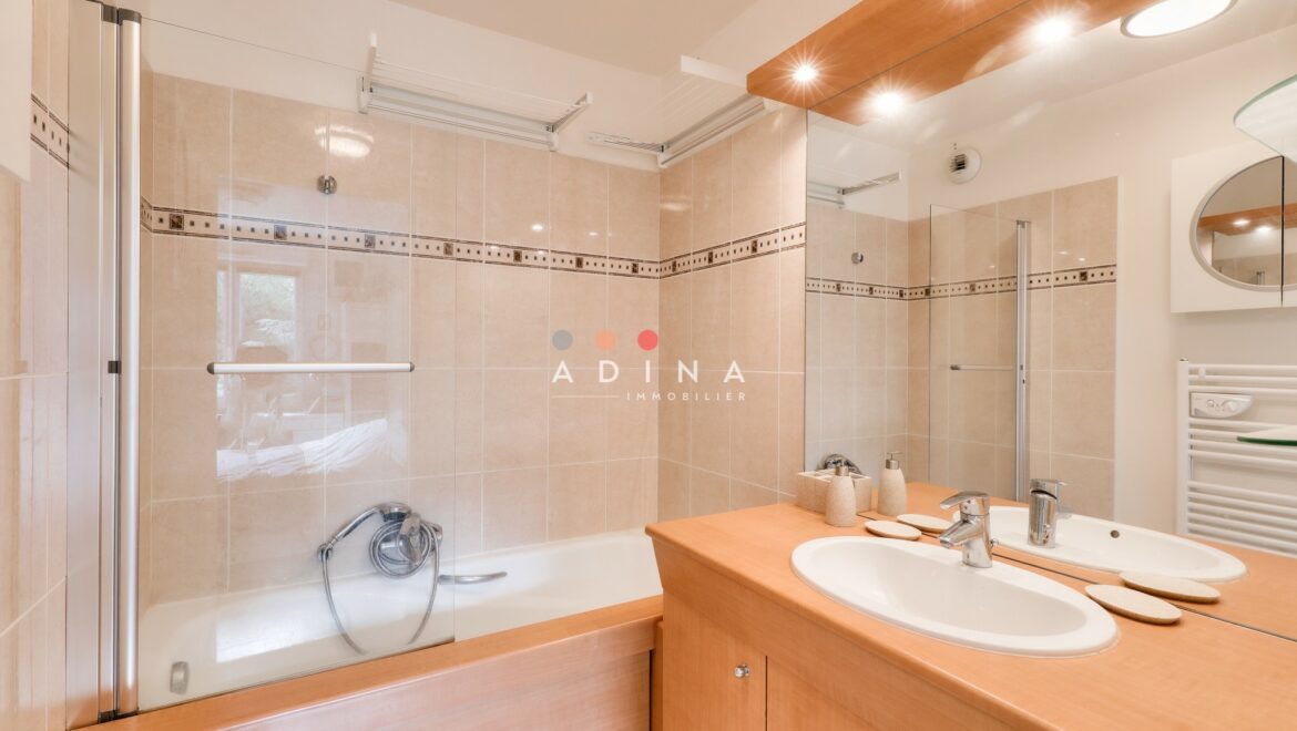 Salle de bains moderne avec double vasque et baignoire.