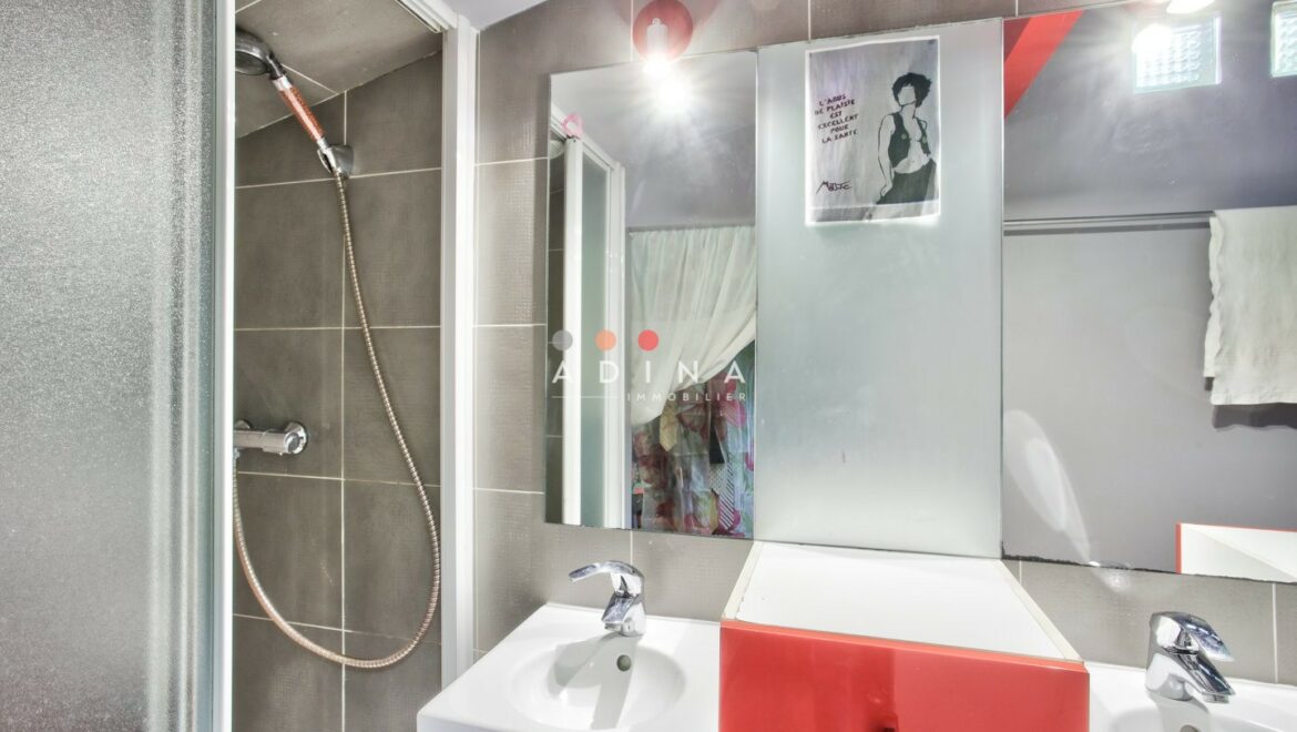 Salle de bain moderne avec douche et lavabo rouge.