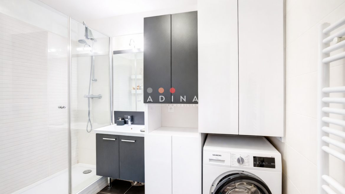 Salle de bain moderne avec douche et lave-linge.