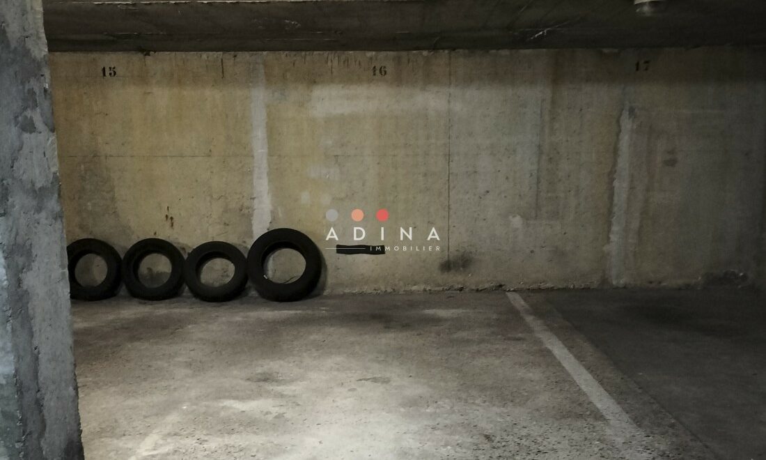 Parking souterrain avec pneus rangés au fond à gauche.