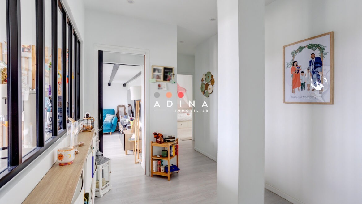 Couloir lumineux avec vue sur salon et décoration murale.