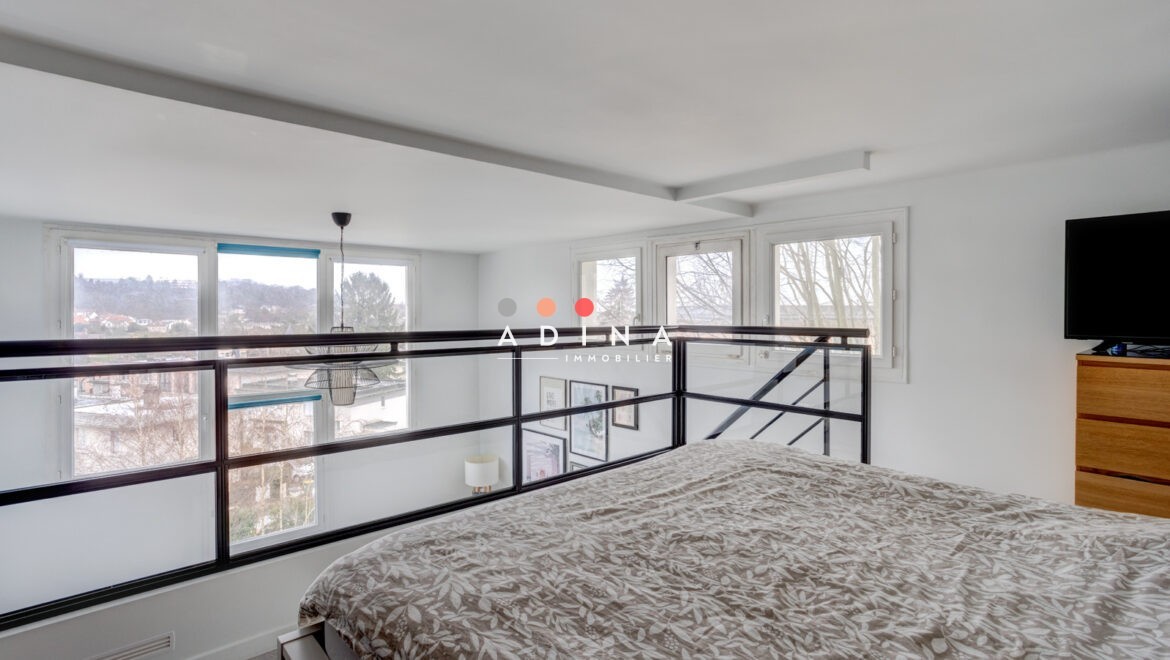 Chambre mezzanine avec grande fenêtre et vue extérieure.