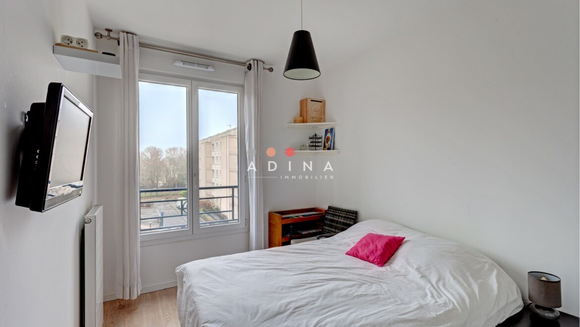 Chambre lumineuse avec fenêtre et lit au Plessis-Robinson.