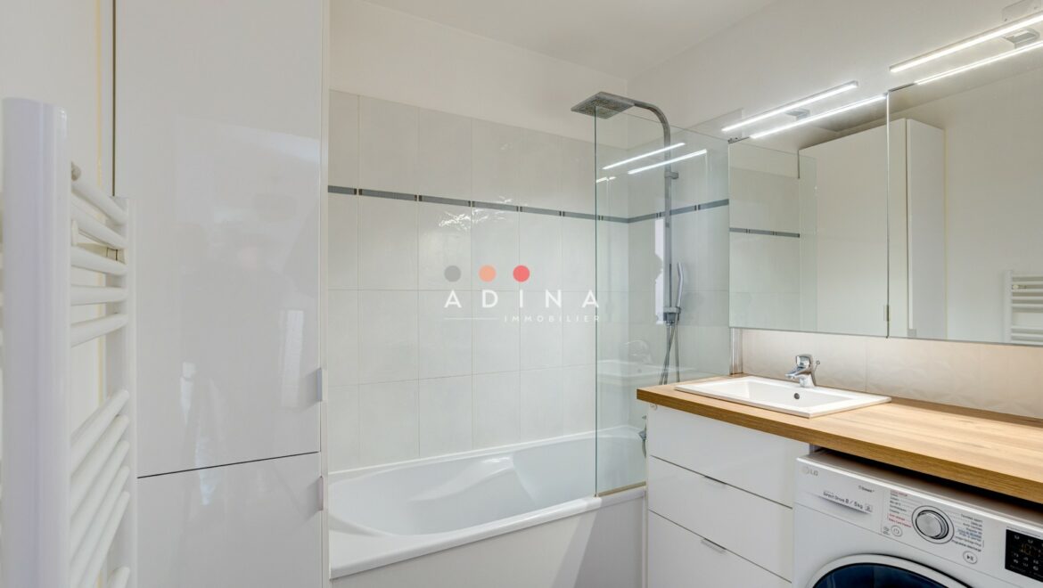 Salle de bain moderne avec baignoire et machine à laver.