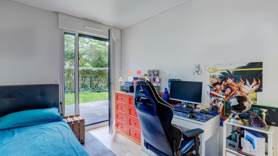 Chambre avec bureau et porte-fenêtre menant à un jardin.