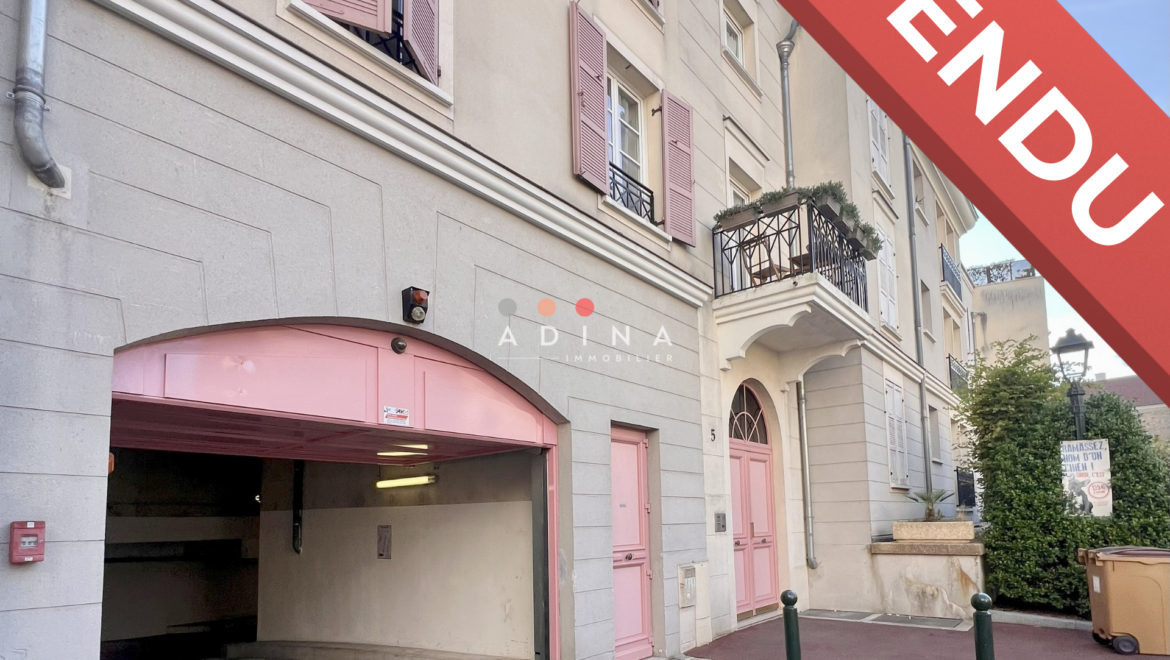 Façade d'un immeuble avec un garage fermé et la mention "Vendu".