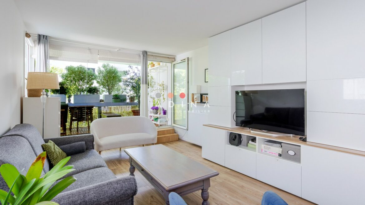 Salon moderne et lumineux avec vue sur un balcon verdoyant.