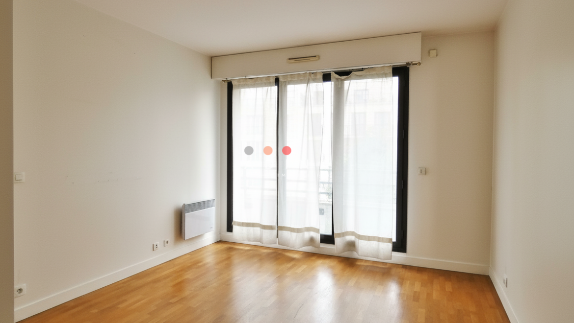 Salle à manger lumineuse avec parquet et grande fenêtre.