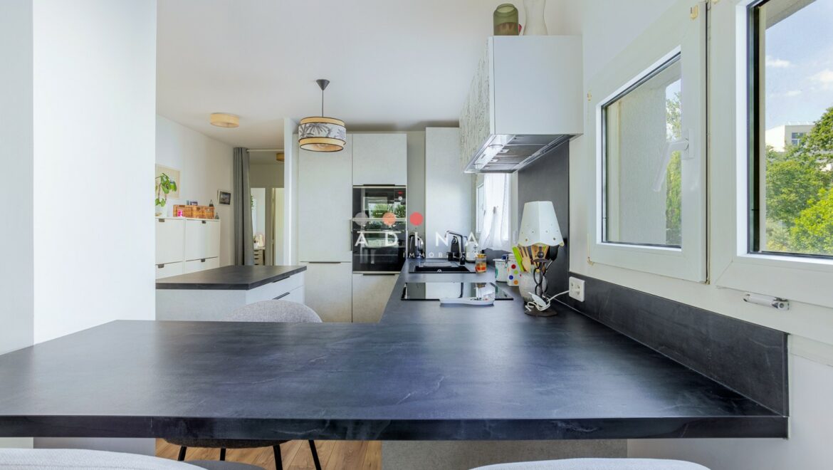 Cuisine moderne et lumineuse avec plan de travail noir.