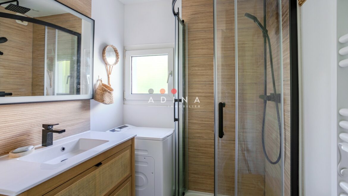 Salle de bain moderne avec douche vitrée et lavabo en bois.