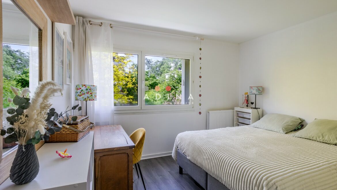 Chambre lumineuse avec fenêtre sur jardin.