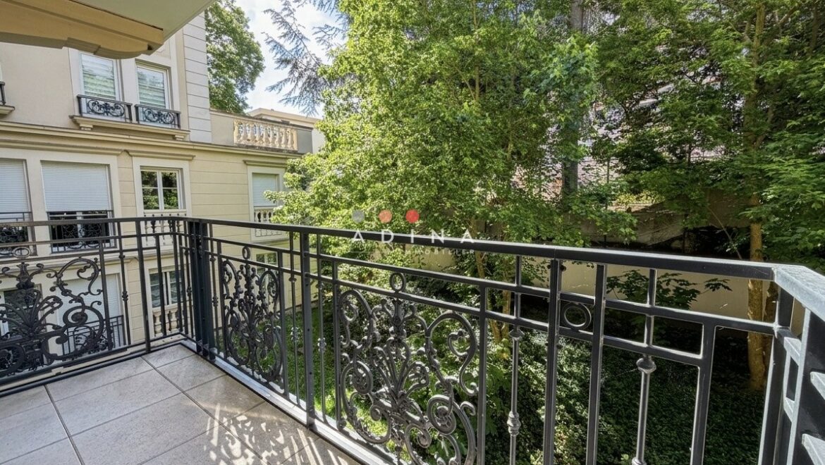 Balcon avec vue sur jardin et bâtiment résidentiel.