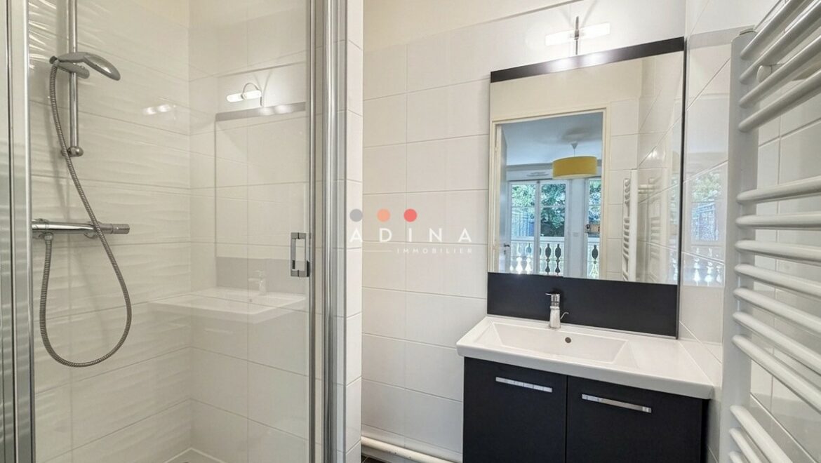 Salle de bain moderne avec douche et lavabo.